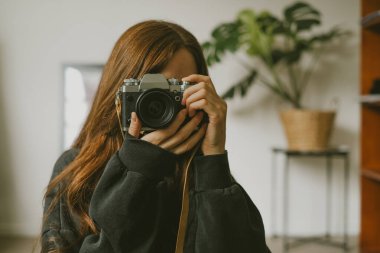 Arka planda canavar bitkisi olan bir aynaya yansıyan uzun saçlı bir kızın portresi.