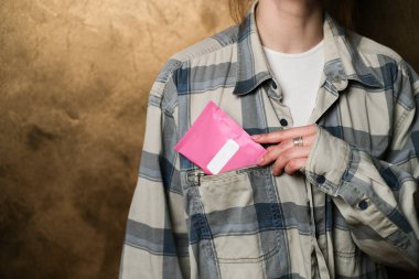Flanel gömleğin cebinde beyaz etiketli küçük pembe bir paket tutan biri. Reklam ya da ürün sergileri için resim modelleme ve proje oluşturma. Ürün maketi. Tasarım konsepti.