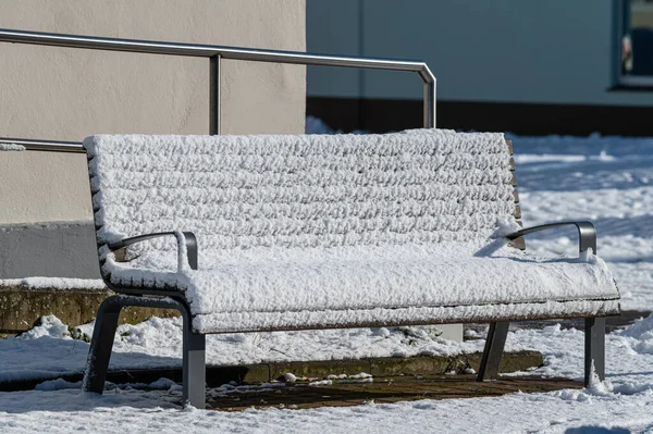 a  snow-covered bench in public at a market place