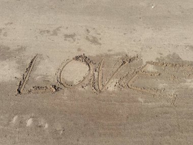 Aşk kelimesi kumsalda yazılıdır.