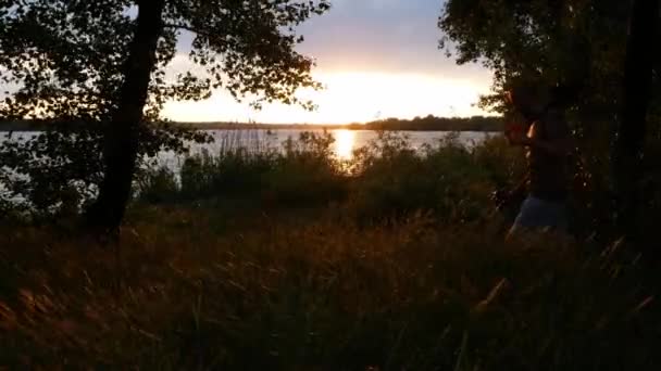 Σιλουέτα Ενός Ανθρώπου Στο Ηλιοβασίλεμα Που Περπατάει Έναν Ανιχνευτή Μετάλλων — Αρχείο Βίντεο
