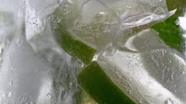 Soğuk limonata mojito kokteyli karbonatlı içecek. Yakın plan soda tazeleyici köpüklü su, bardakta nane ve limon, buz küpleri. Limon dilimi, mineral köpükleri. Sağlıklı beslenme.