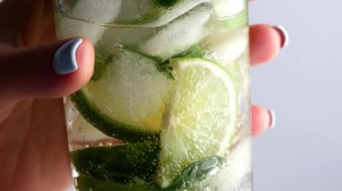 Soğuk limonata mojito kokteyli karbonatlı içecek. Yakın plan soda tazeleyici köpüklü su, bardakta nane ve limon, buz küpleri. Limon dilimi, mineral köpükleri. Sağlıklı beslenme.