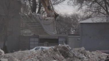 Kova Kazıyıcı 'nın yakın çekimi bir yıkım alanındaki çöpten kurtulmaya çalışıyor. Eski bir binadan inşaat malzemelerinin sökülmesi.