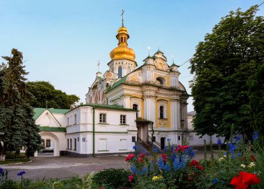 Günbatımında Kyiv Pechersk Lavra 'nın antik mimarisi ve ön planda çiçekler