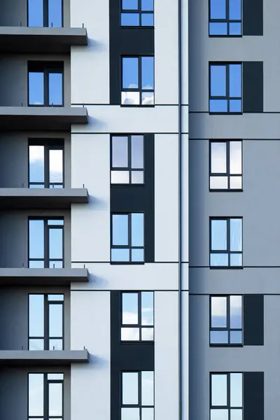 Stock image A part of modern residential building facade with reflection of blue sky in windows