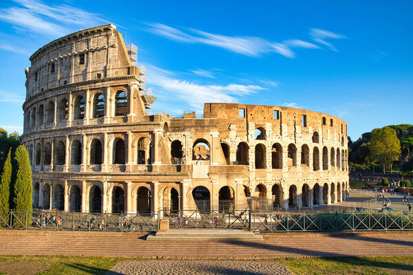 View on the Collosseum from the Forum Romanum on a sunny day and with visitors in the Collosseum