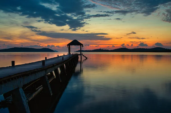 A jetty in the sunset on Coron Island with a small hut at the end and colorful sky.