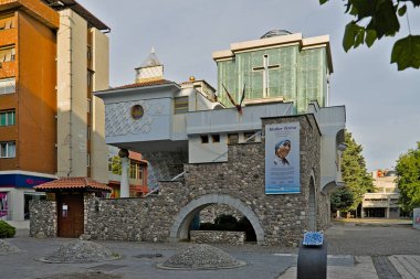 Üsküp 'te Rahibe Teresa' nın anma töreni ve sağ üst köşede yeşil yapraklar