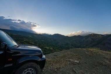 Kurak yaz koşullarına rağmen yeşil manzaralı Hotova Dangell milli park manzarası. Sol tarafta, bu pist için zorunlu olan off-road arabamızın görünen ucu var.
