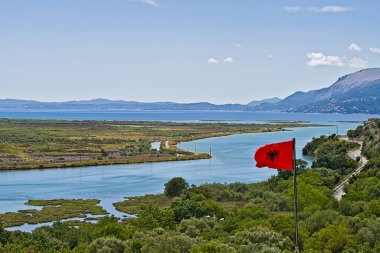 View from the castle in Butrint on the surounding with the Albanian flag waving in the wind clipart