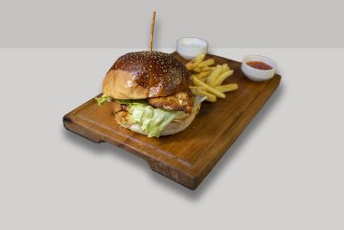 Kızarmış tavuk burger, patates kızartması ve salata sosu beyaz arka planda izole edilmiş tahtanın üzerinde..