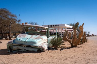 Namibya 'daki Solitaire tabelasının önünde yarı batmış eski terk edilmiş bir kamyon.