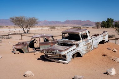 İki eski, terk edilmiş araba, Namibya 'da çölde kumlara gömülmüş.