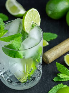 Kesik bir cam bardakta kesilmiş taze nane ve limondan yapılmış bir mojito kokteyli.