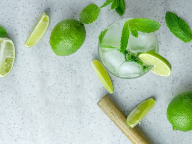 Taze naneli ve limonlu mojito kokteylinin soluk bir arka planda kesilmiş cam bir bardak bardaktaki görüntüsü.