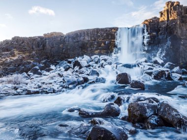 Frozen water on the rocks around the base of a waterfall in Thingvellir in central Iceland clipart