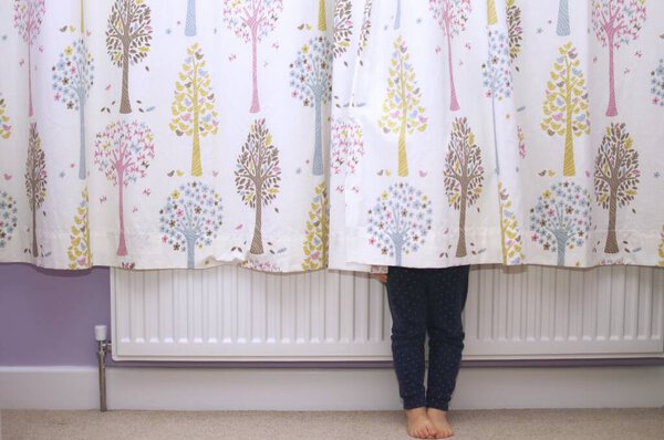 A child hiding behind curtains so you can only see their legs