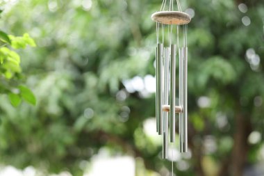 Wind chimes with green blurred background. Metal wind chimes with blurred background. clipart