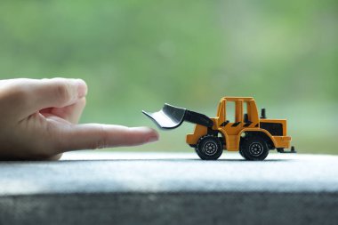 Bir çocuğun eli oyuncak kazıcıya dokunur. Bulanık arka planı olan çocuk eli ve oyuncak kazıcısı. 