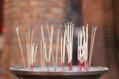 Tütsü çubukları, yukarıdan yükselen dumanla bir tencereye sıkışmış. Kutsal nesnelere ibadet etmek için yakılan tütsü çubukları tütsü kabına konur..