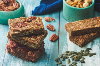 Enerji Çubukları ve Karışık Fındıklar Mavi Tahta Masa 'da. Ceviz, Fıstık, Fındık, Badem, Fıstık, Fıstık