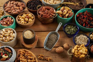 Tahta bir masada farklı kaselerde fındık karışımı. Ceviz, Fıstık, Fındık, Badem, Fıstık, Fıstık, Fıstık, Kayısı, Kuru üzümler, Tarihler, Hindistan Cevizi