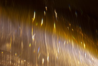 Parlayan çizgilerin ve lekelerin odaksız arka planı. Işık parçacıklarının hareketi kavramı.