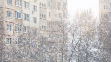 Defocused winter background. Winter city.Defocused background of high-rise buildings, trees and falling snow.