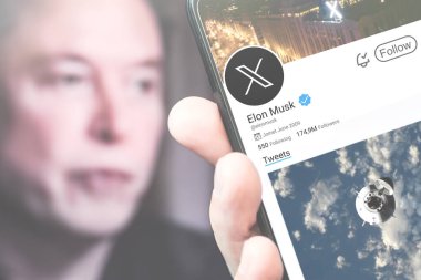 Poltava, Ukrayna - 5 Mart 2024: Elon Musk 'ın Twitter profili akıllı telefon ekranında. Arka planda Elon Musk 'ın çözülmüş bir portresi var. Yumuşak odaklanma. Resimli editör fotoğrafçılığı.