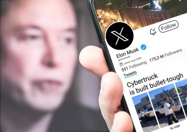 Poltava, Ukrayna - 5 Mart 2024: Elon Musk 'ın akıllı telefon ekranındaki Twitter profili ve Siber kamyon hakkındaki yeni tweeti. Arka planda Elon Musk 'un odak dışı bir portresi var..