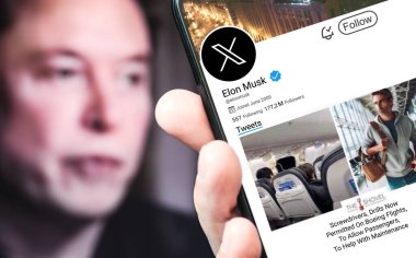 Poltava, Ukrayna - 17 Mart 2024: Elon Musk Twitter profili sayfası elinde bir akıllı telefonla. Arka planda Elon Musk 'un odaksız bir portresi var..