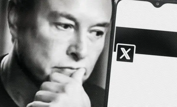 Elon Musk, üzerinde yeni Twitter logosu olan akıllı telefona bakıyor. Akıllı telefonunuzdaki alanı kopyalayın.