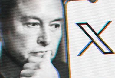 Dalgın Elon Musk, üzerinde yeni Twitter logosu olan akıllı telefona bakıyor. Akıllı telefonunuzdaki alanı kopyalayın.