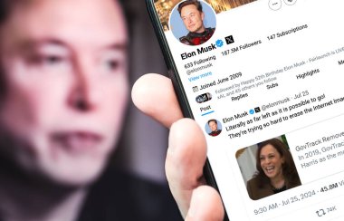 Ukrayna. Poltava. 25 Temmuz 2024. Elon Musk 'ın profili akıllı telefon ekranında. Mesajlı yeni tweet. - Evet. Arka planda Elon Musk 'un odaksız bir portresi var..