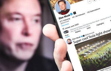 Ukrayna. Poltava. 27 Temmuz 2024. Elon Musk 'ın profili akıllı telefon ekranında. Mesajlı yeni tweet. Arka planda Elon Musk 'un odaksız bir portresi var..