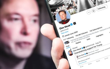 Poltava, Ukraine - August 22, ,2024. Elon Musk Twitter profile page with a smartphone in his hand. In the background is a defocused portrait of Elon Musk. clipart