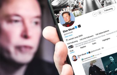 Poltava, Ukrayna - 30 Ağustos 2024. Elon Musk Twitter profili sayfasında elinde akıllı telefon var. Arka planda Elon Musk 'un odaksız bir portresi var..