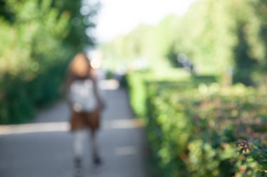 Geçmişi bulanık, parkta yürüyen kimliği belirsiz genç bir kadın. Yaz güneşli bir gün,