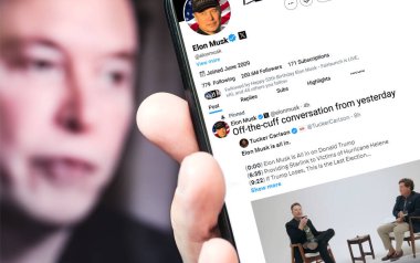 Poltava, Ukrayna, Ekim 08, 2024. Elon Musk Twitter profili, akıllı telefon ekranında Tucker Carlson 'la bir konuşma hakkında yeni bir tweet atıyor. Arka planda Musk 'ın odaksız bir portresi var..