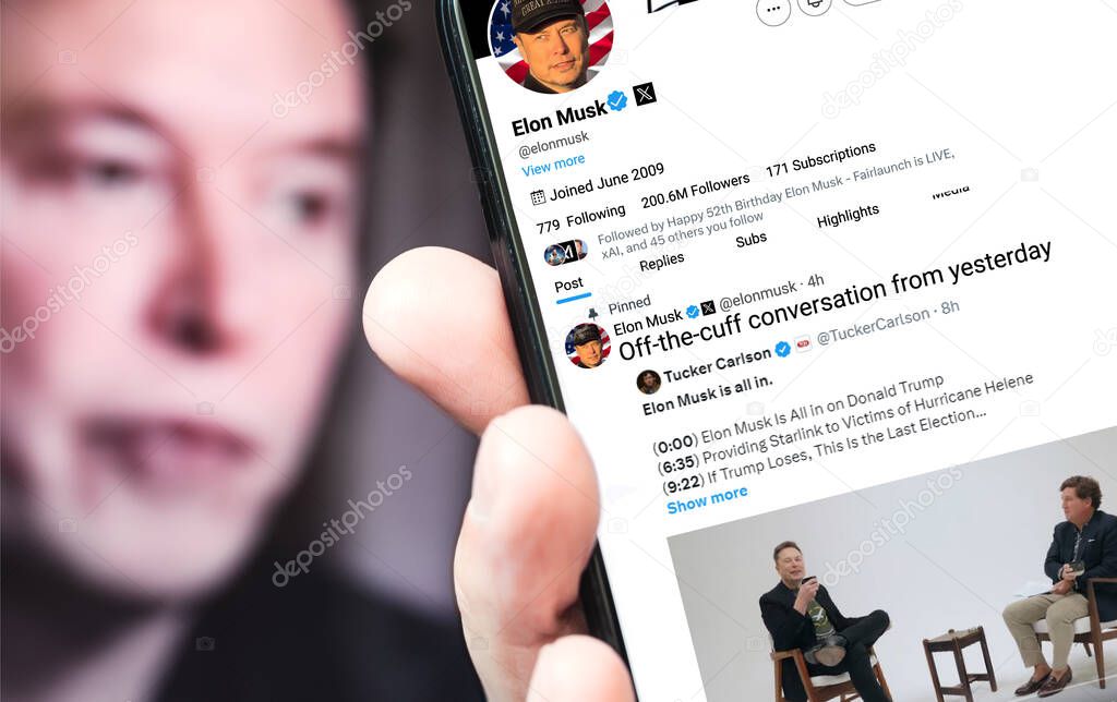 Poltava, Ukraine, October 08, 2024. Elon Musk Twitter profile page on a smartphone screen with a new tweet about a conversation with Tucker Carlson. In the background is a defocused portrait of Musk.