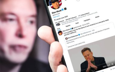 Poltava Ukrayna 08 Ekim 2024. Elon Musk Twitter profili, yeni bir tweet ile akıllı telefon ekranında. Arka planda Musk 'ın odaksız bir portresi var..