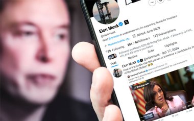 Ukrayna. Poltava. 17 Ekim 2024. Elon Musk profili akıllı telefon ekranında. Mesajlı yeni tweet. Arka planda Elon Musk 'un odaksız bir portresi var..