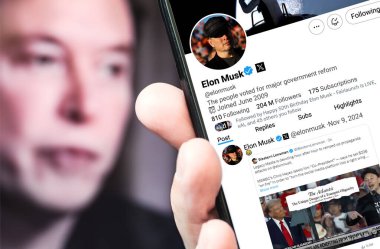 Boryspil Ukrayna 9 Kasım 2024. Elon Musk Twitter profili yeni bir tweet ile akıllı telefon ekranında.. Arka planda Musk 'ın odaksız bir portresi var..