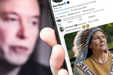 Poltava, Ukrayna - 17 Aralık 2024. Elon Musk Twitter profili sayfasında elinde akıllı telefonuyla yeni bir tweet var. Arka planda Elon Musk 'un odaksız bir portresi var..