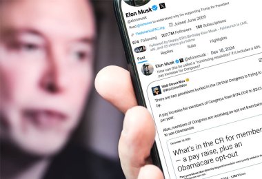 Poltava, Ukrayna - 18 Aralık 2024. Elon Musk Twitter profili sayfasında elinde akıllı telefonuyla yeni bir tweet var. Arka planda Elon Musk 'un odaksız bir portresi var..