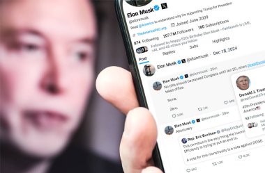 Poltava, Ukrayna - 18 Aralık 2024. Elon Musk Twitter profili sayfasında elinde akıllı telefonuyla yeni bir tweet var. Arka planda Elon Musk 'un odaksız bir portresi var..