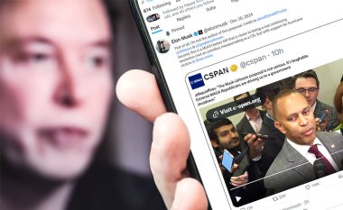 Poltava, Ukrayna - 20 Aralık 2024. Elon Musk Twitter profili sayfasında elinde akıllı telefonuyla yeni bir tweet var. Arka planda Elon Musk 'un odaksız bir portresi var..