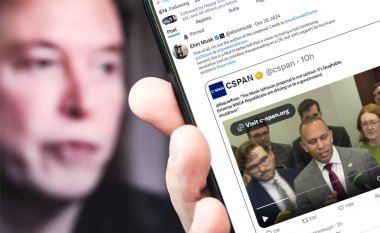 Poltava, Ukrayna - 20 Aralık 2024. Elon Musk Twitter profili sayfasında elinde akıllı telefonuyla yeni bir tweet var. Arka planda Elon Musk 'un odaksız bir portresi var..