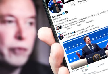 Poltava, Ukrayna - 21 Ocak 2025. Elon Musk Twitter profili sayfasında elinde akıllı telefonuyla yeni bir tweet var. Arka planda Elon Musk 'un odaksız bir portresi var..